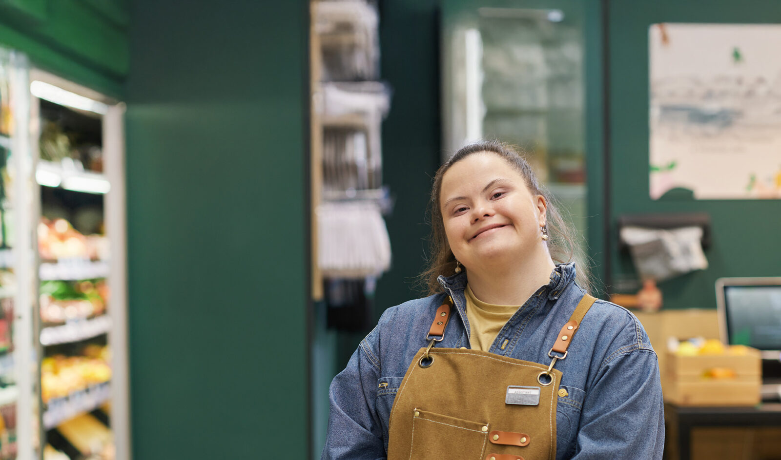portrait of smiling young woman with Down syndrome enjoying work in supermarket